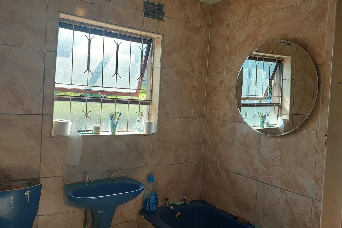 A dated bathroom featuring tiled walls, a blue pedestal basin, and a matching built-in bathtub, requiring cosmetic updates to modernize the space.
