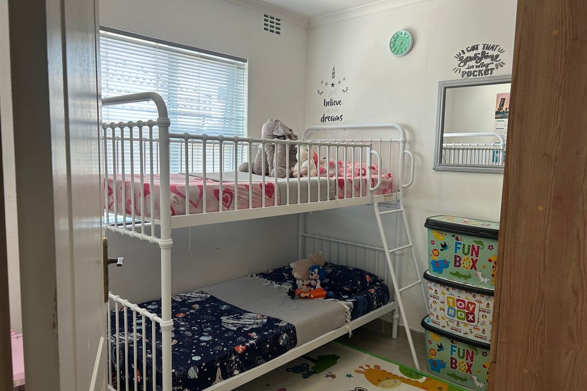A functional bedroom featuring a window with venetian blinds and decorative coving, suitable for a child's room or guest space.