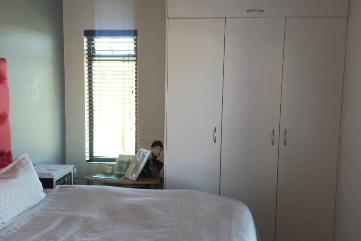 A bedroom featuring a built-in wardrobe with white doors and a window fitted with venetian blinds.