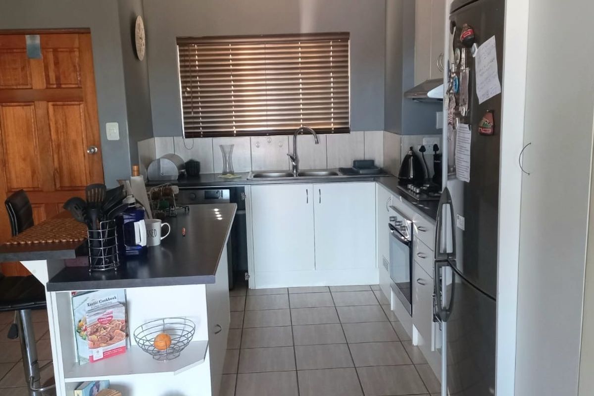 A functional kitchen featuring white cabinetry, tiled backsplash, built-in oven with hob, and tiled flooring, offering a practical layout for daily meal preparation.