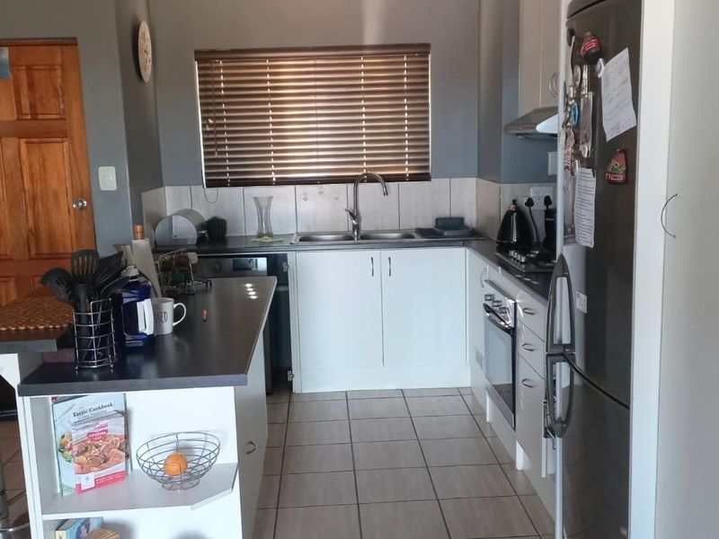 A functional kitchen featuring white cabinetry, tiled backsplash, built-in oven with hob, and tiled flooring, offering a practical layout for daily meal preparation.