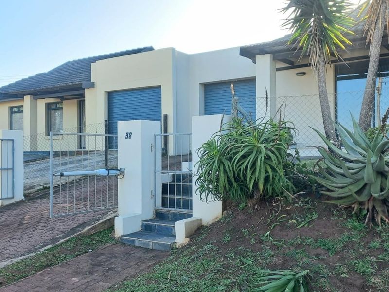 Front view of a residential property featuring a double garage with roller shutter doors, a paved driveway, and a gated entrance.