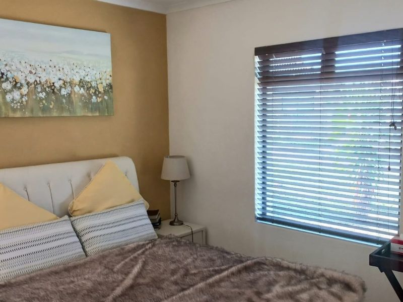 A well-maintained bedroom featuring neutral wall tones and fitted venetian blinds, providing a comfortable and functional living space.