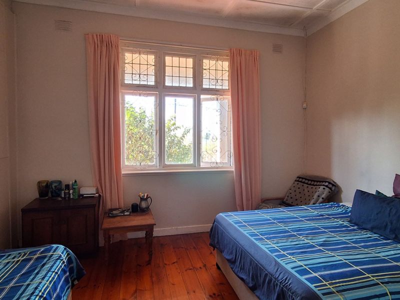 A bedroom featuring original timber flooring, security-barred windows, and classic cornice detailing, offering a blank canvas for renovation and modernization.