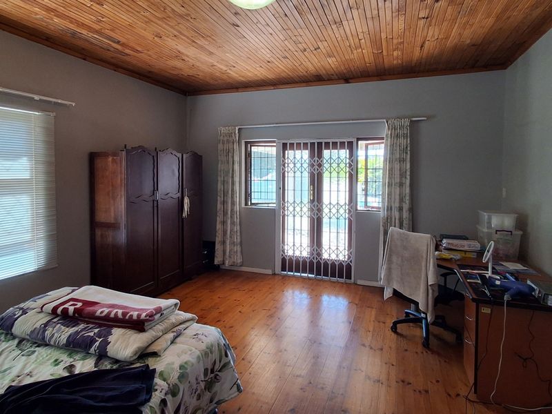 Spacious bedroom featuring warm timber ceiling and flooring, with direct access to the exterior through a secure gate.