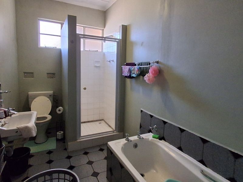 A functional bathroom featuring a separate shower enclosure, bathtub, pedestal basin, and toilet with classic tiled flooring and splashback finishes.