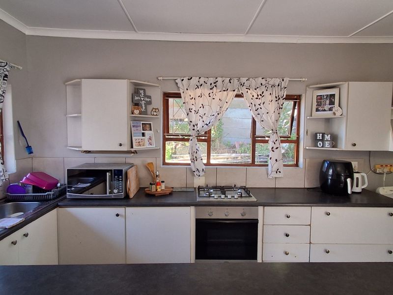 Functional kitchen featuring built-in cabinetry, laminate countertops, a gas hob, and an integrated oven with a tiled splashback and natural light.