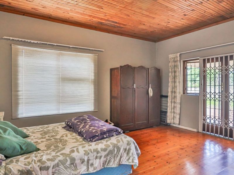 Spacious bedroom featuring warm timber flooring and a classic timber ceiling, with direct access to the exterior through a secure sliding door.