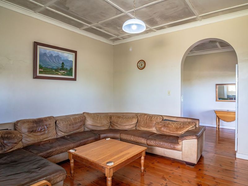 A living room featuring original timber flooring, a distinctive coffered ceiling, and an arched entryway leading to an adjacent space.