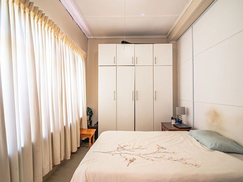 A bedroom featuring a large built-in wardrobe and floor-to-ceiling curtains, providing ample storage and natural light.