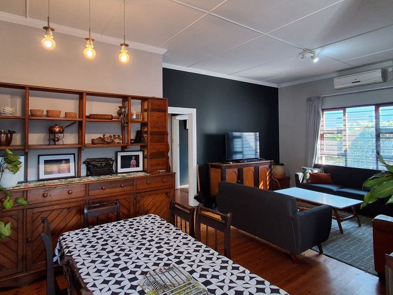Spacious open-plan living and dining area featuring polished hardwood floors, modern pendant lighting, and a split-system air conditioner for climate control.
