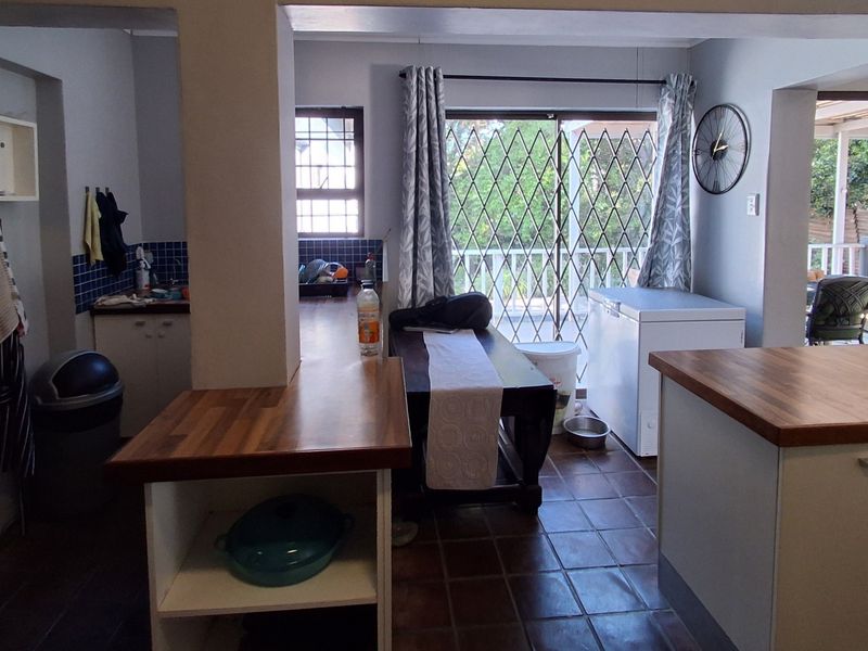 Open plan kitchen and dining area featuring tiled flooring, wooden countertops, and direct access to an outdoor patio through a sliding security gate.