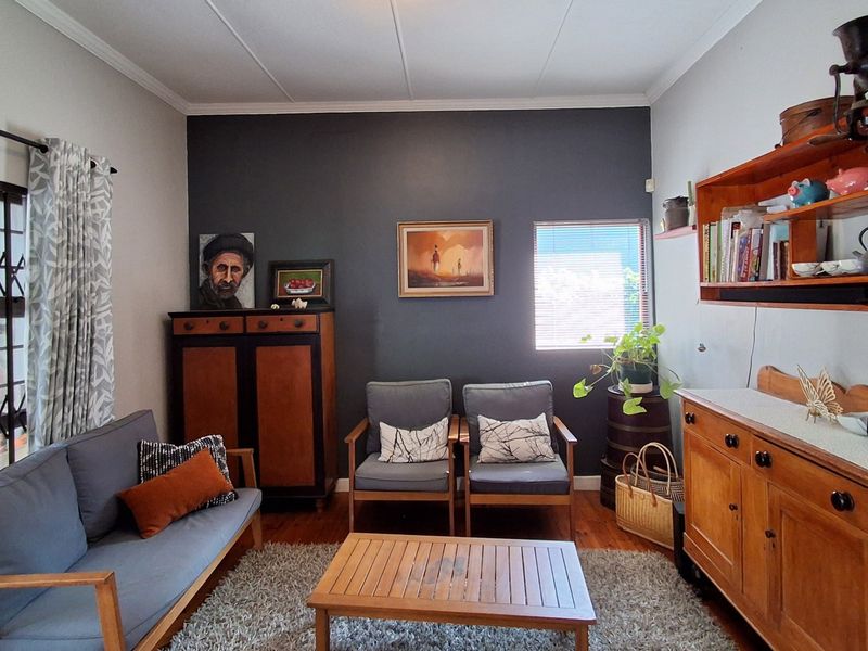 A cozy living room featuring hardwood flooring, a dark accent wall, and a sliding door with a security gate leading to the exterior.