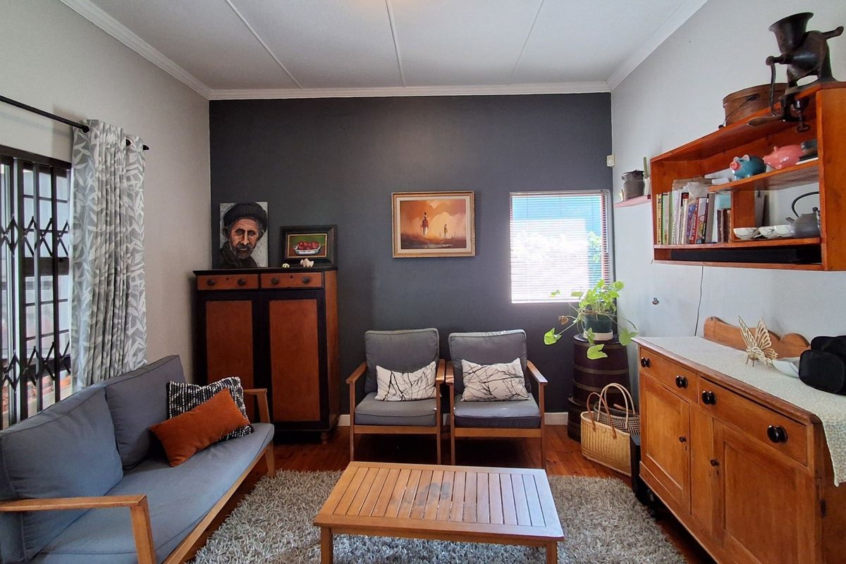 A cozy living room featuring hardwood flooring, a dark accent wall, and a sliding door with a security gate leading to the exterior.