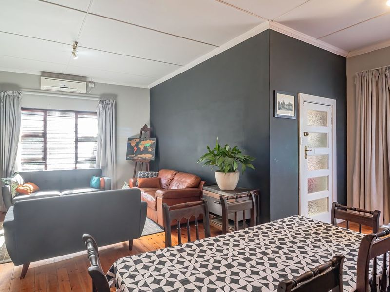Open plan living and dining area featuring timber flooring, split-system air conditioning, and direct access to an outdoor space through a glass panel door.
