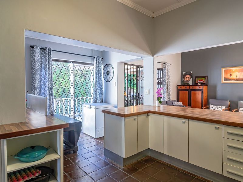 Open-plan kitchen and living area featuring tiled floors, butcher block countertops, and direct access to an outdoor patio through sliding security doors.