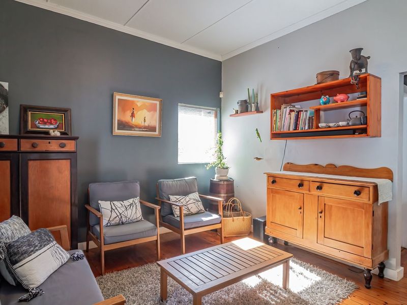 A cozy living room featuring warm hardwood flooring, a coved ceiling, and a neutral color palette with a dark accent wall.