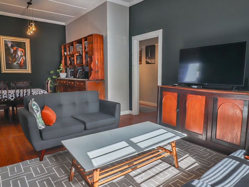An open-plan living and dining area featuring dark painted walls, traditional timber flooring, and classic architectural cornicing details.
