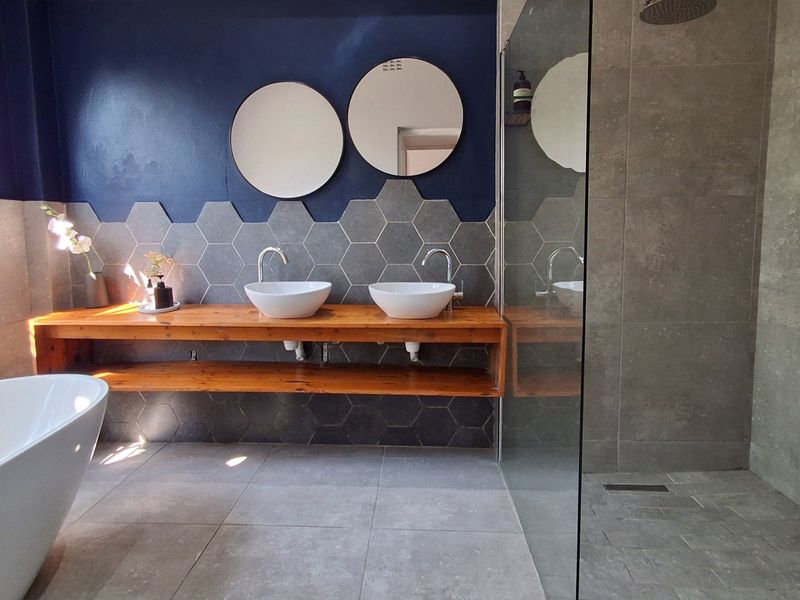 Modern bathroom featuring a double vanity with vessel sinks, a freestanding bathtub, and a spacious walk-in shower with contemporary grey tiling.