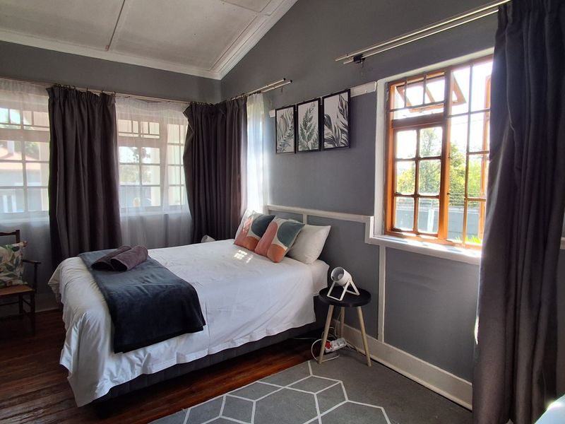 A bedroom featuring timber flooring, vaulted ceilings, and classic timber-framed windows, offering a cozy atmosphere with traditional architectural details.