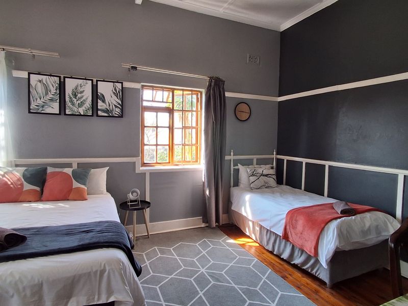 A spacious bedroom featuring hardwood flooring, classic picture rails, and a timber-framed window, providing a comfortable and well-maintained living space.
