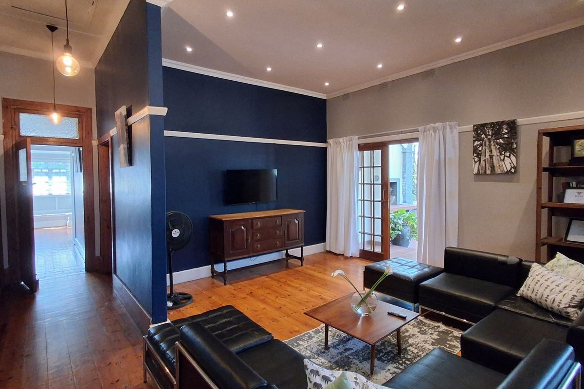 Spacious living room featuring polished timber flooring, recessed downlighting, and classic picture rails, with direct access to the outdoor area through french doors.