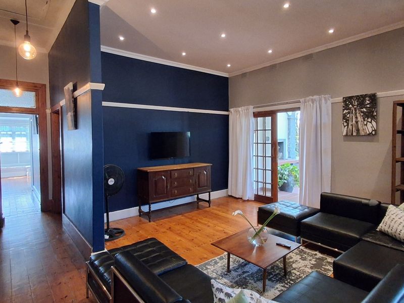 Spacious living room featuring polished timber flooring, recessed downlighting, and classic picture rails, with direct access to the outdoor area through french doors.