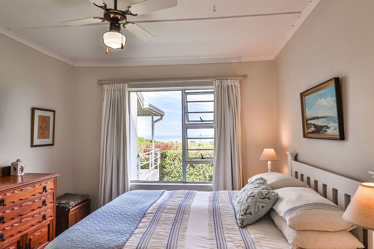 A well-maintained bedroom featuring a ceiling fan and a window with views of the exterior surroundings.