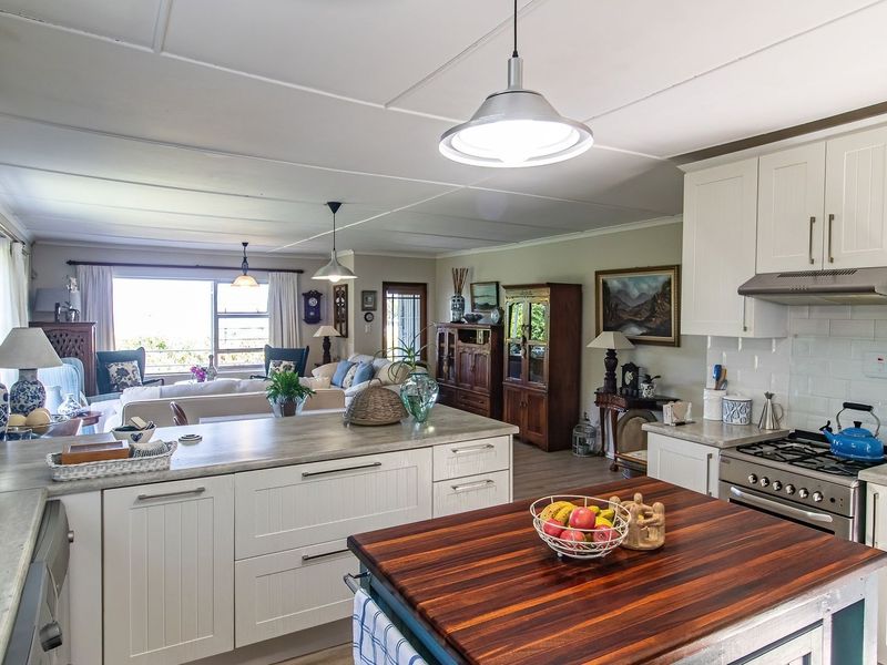 Spacious open-plan kitchen and living area featuring white cabinetry, gas cooktop, timber island, and ample natural light, creating a warm and functional home heart.
