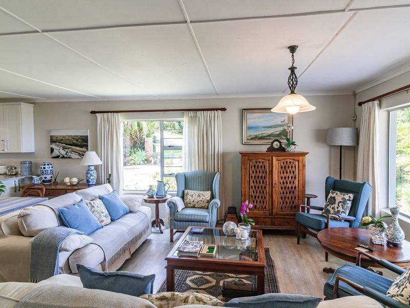 Spacious open-plan living and kitchen area featuring laminate flooring, ample natural light, and integrated kitchen cabinetry with a functional island layout.