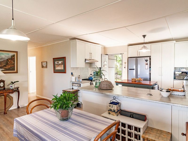 Spacious open-plan kitchen and dining area featuring white cabinetry, stone countertops, and a functional kitchen island, creating a bright and inviting living space.