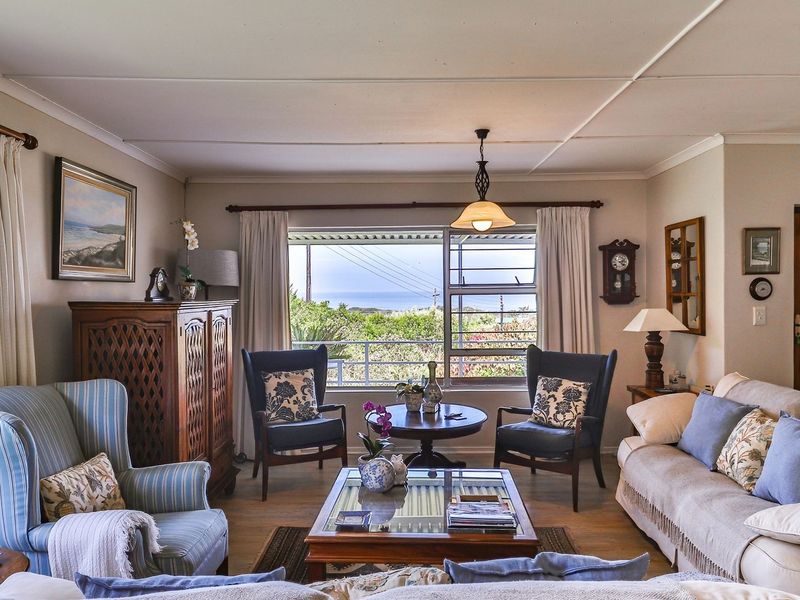 A comfortable living room featuring louvered windows with a scenic view, neutral wall finishes, and a classic ceiling design.