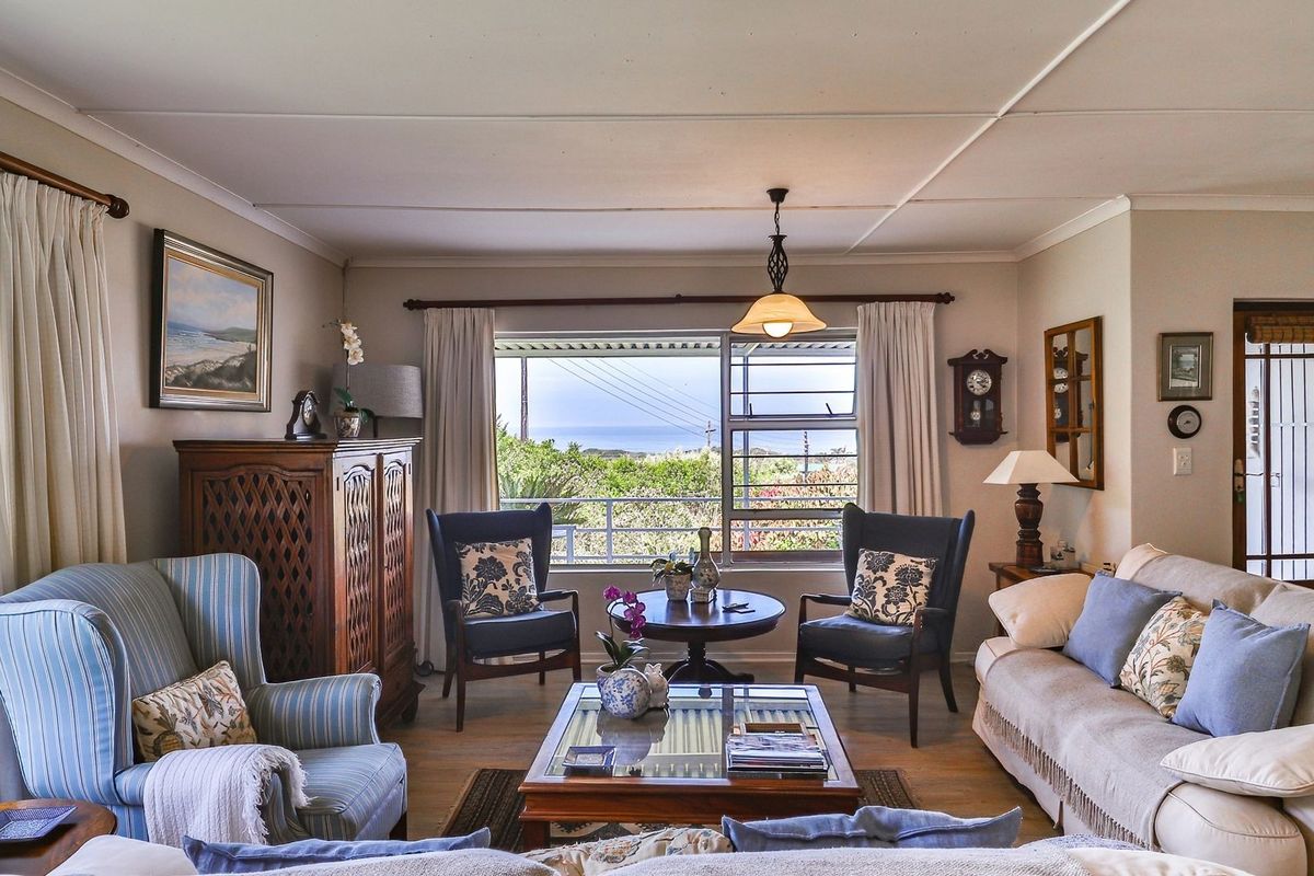 A comfortable living room featuring louvered windows with a scenic view, neutral wall finishes, and a classic ceiling design.