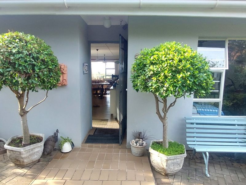 Front entrance area featuring a paved patio, security gate, and aluminium window frames, providing a welcoming access point to the home.