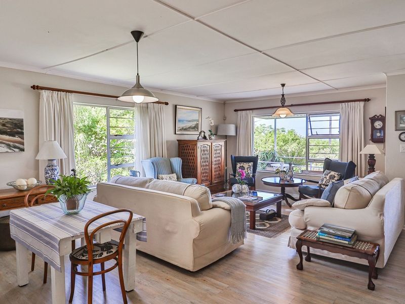 Spacious open-plan living and dining area featuring laminate flooring, large windows with natural light, and direct access to an outdoor space.