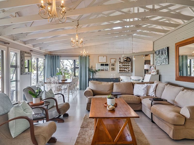 Spacious open-plan living and dining area featuring vaulted ceilings with exposed rafters, laminate flooring, and large sliding doors leading to an outdoor patio.