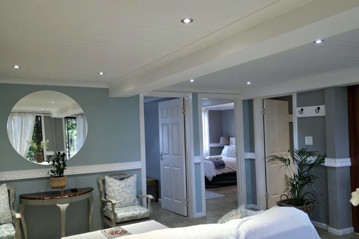 A well-maintained living area featuring recessed downlighting, decorative chair rail molding, and neutral tiled flooring, providing access to adjacent bedrooms.