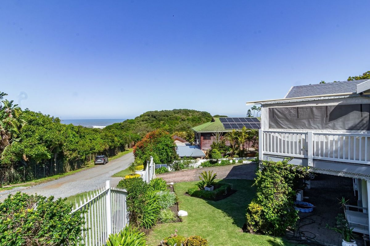 A view of the rear garden and property exterior, featuring a raised deck, solar panels, and a landscaped yard with coastal views.