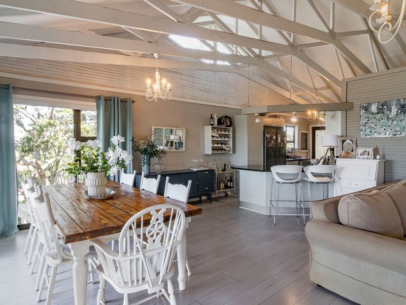 Spacious open-plan living and dining area featuring a vaulted ceiling with exposed timber trusses, laminate flooring, and a functional kitchen island.