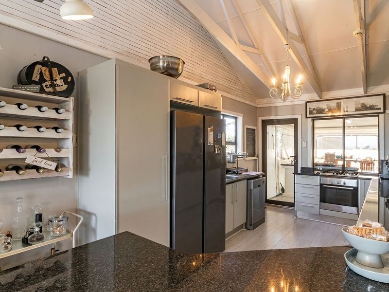 A well-appointed kitchen featuring granite countertops, built-in cabinetry, integrated appliances, and a vaulted ceiling with exposed timber beams, offering a bright and functional space.