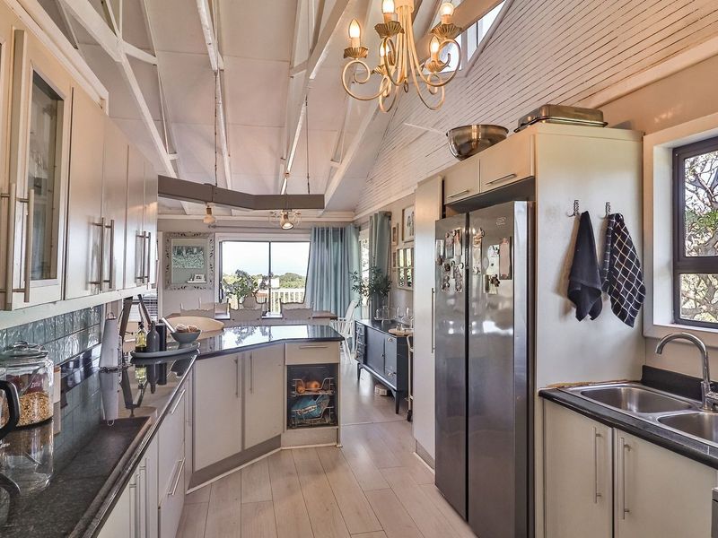 Spacious open-plan kitchen featuring granite countertops, ample cabinetry, and a vaulted ceiling with exposed rafters, flowing seamlessly into the dining area.