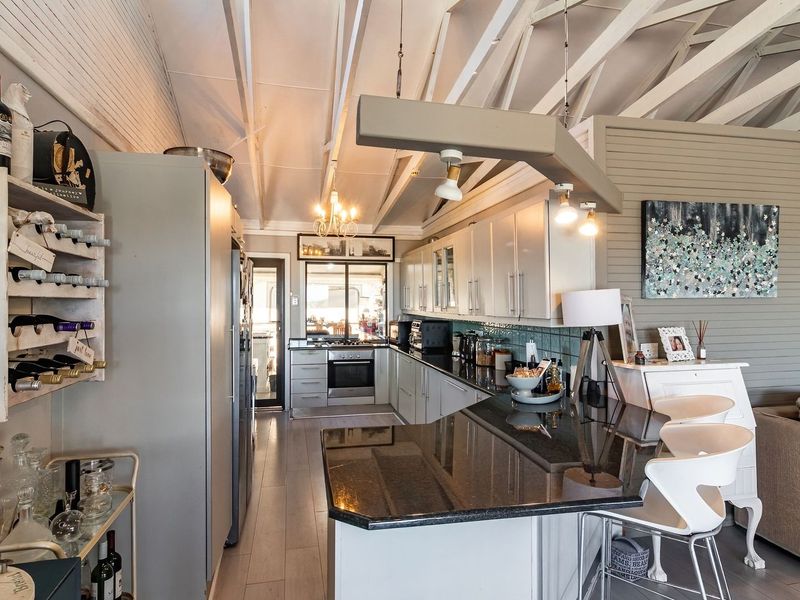 Spacious open-plan kitchen featuring granite countertops, built-in appliances, and exposed timber rafters, seamlessly integrated with the living area.