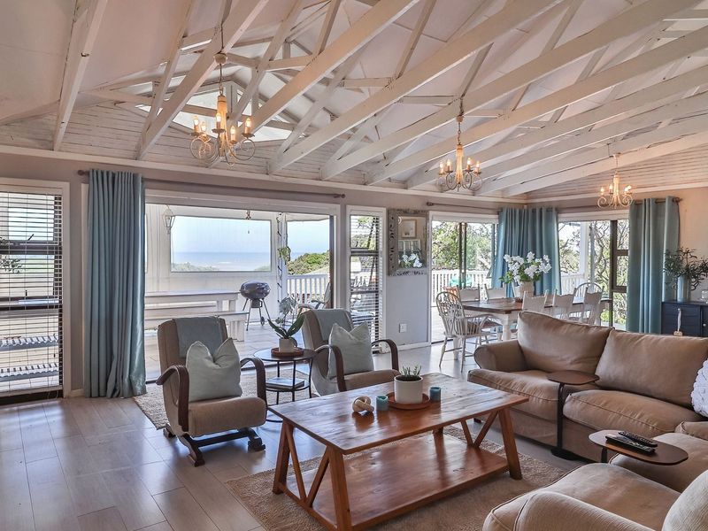 Spacious open-plan living and dining area featuring a vaulted ceiling with exposed timber rafters, laminate flooring, and large sliding doors leading to a patio.
