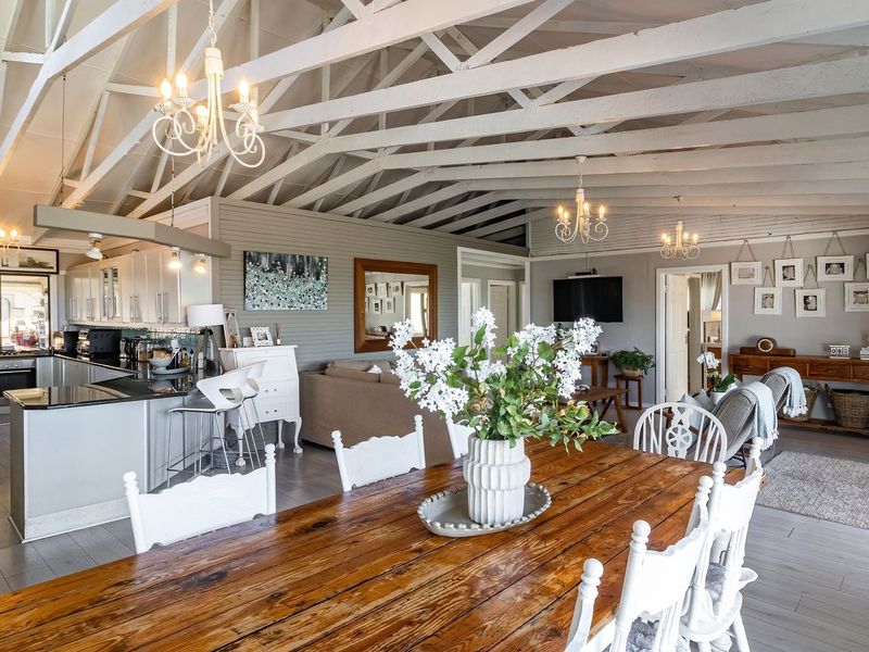 Spacious open-plan living, dining, and kitchen area featuring high vaulted ceilings with exposed white timber trusses and modern finishes.