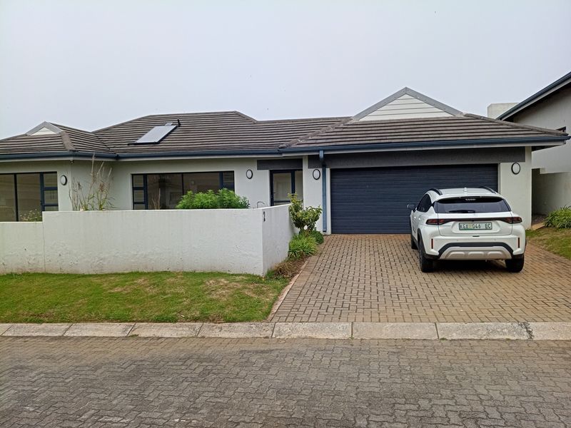 Front elevation of a single-story house featuring a tiled roof with solar heating, a paved driveway, and an automated garage door.