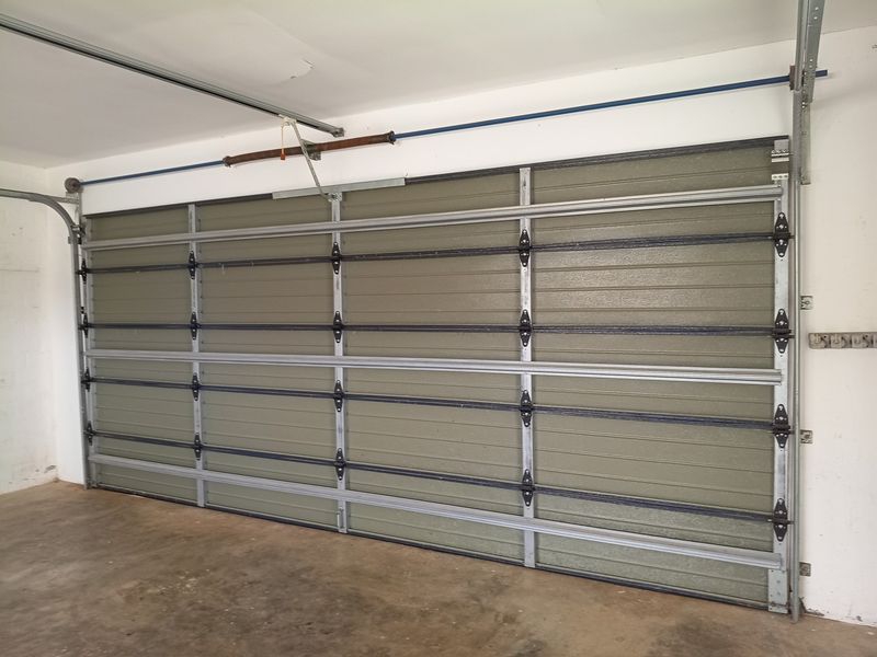 A functional double garage space featuring a sectional door mechanism and concrete flooring.