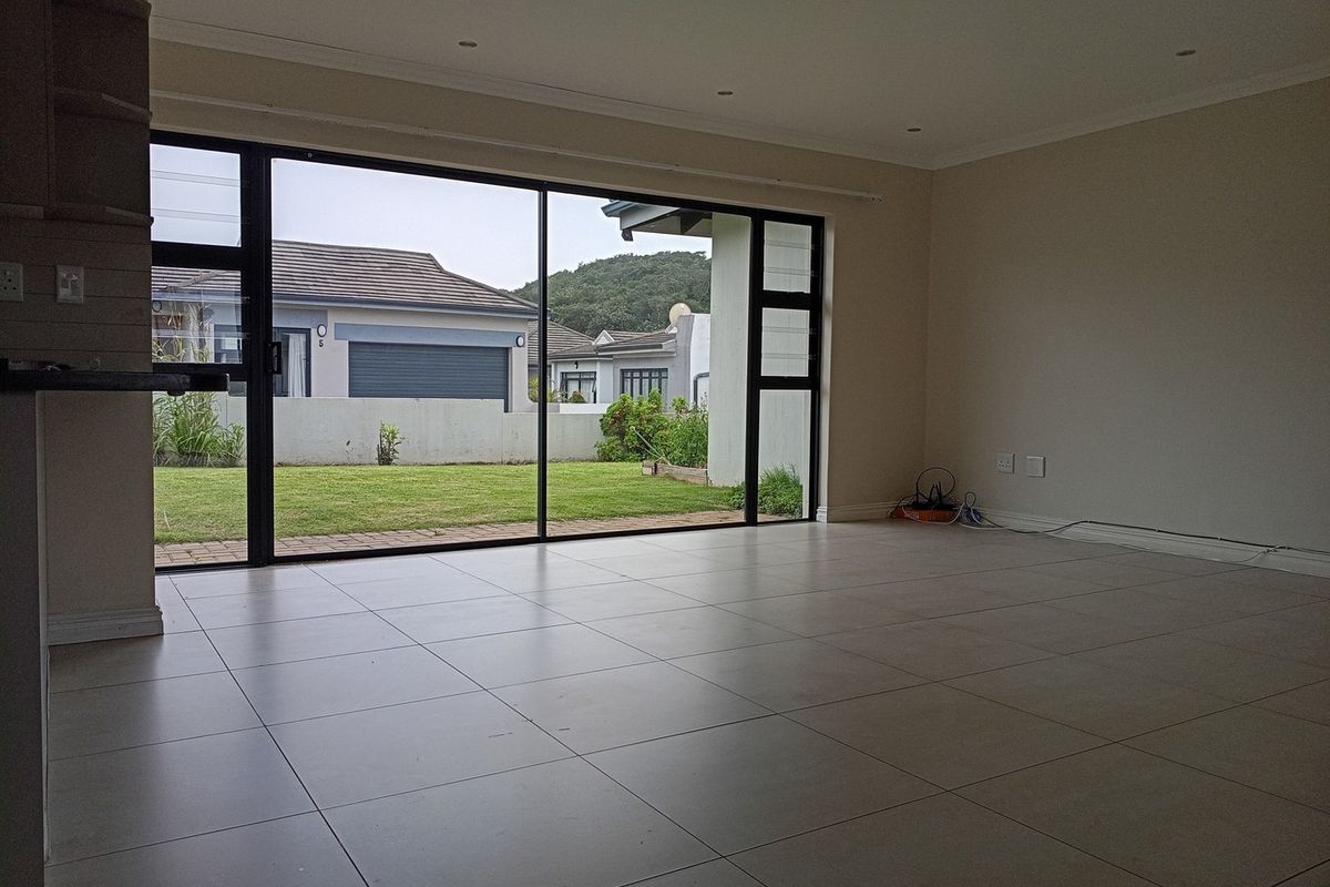 Spacious, empty living area featuring large sliding glass doors that provide ample natural light and direct access to the rear garden.