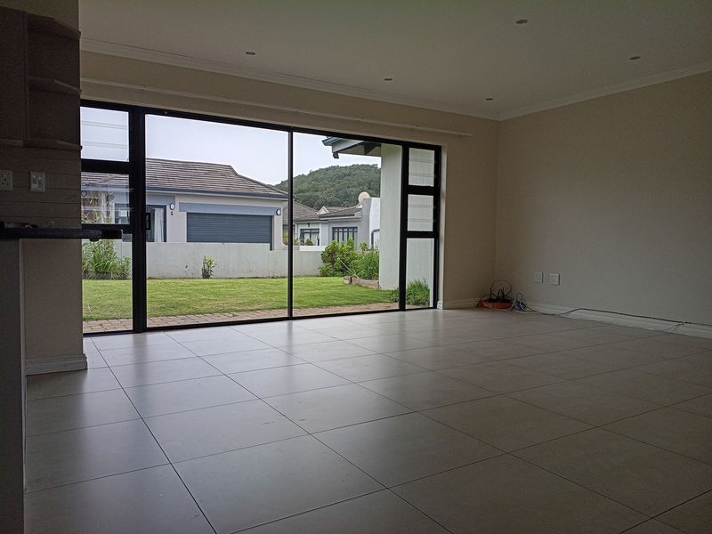 Spacious, empty living area featuring large sliding glass doors that provide ample natural light and direct access to the rear garden.