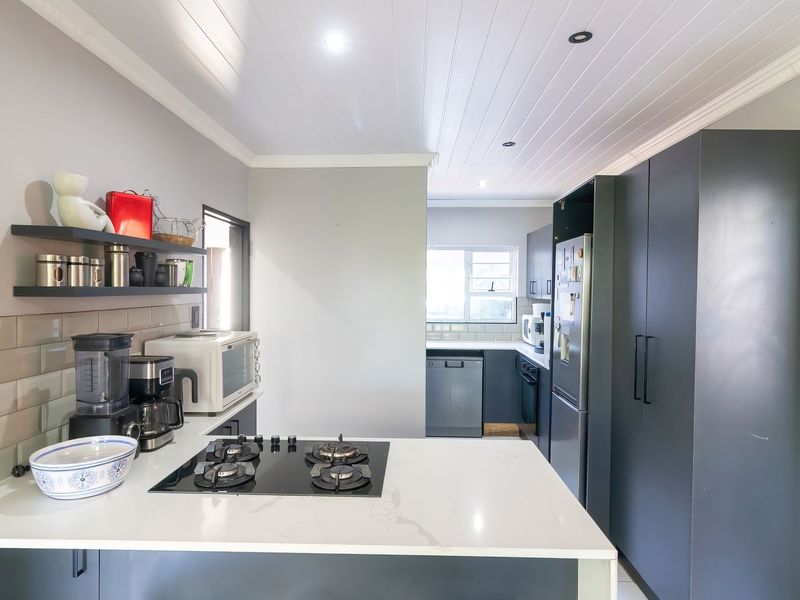 Modern kitchen featuring dark cabinetry, quartz countertops, a gas hob, subway tile backsplash, and a clean tongue and groove ceiling finish.