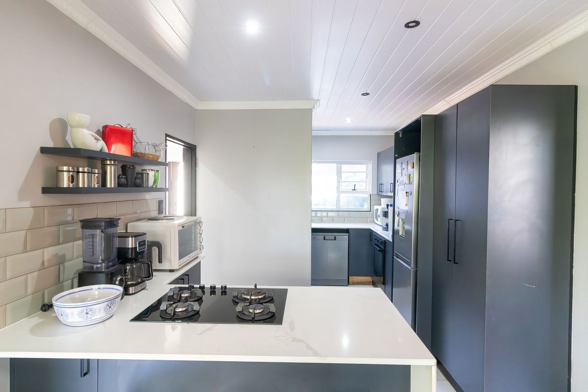 Modern kitchen featuring dark cabinetry, quartz countertops, a gas hob, subway tile backsplash, and a clean tongue and groove ceiling finish.